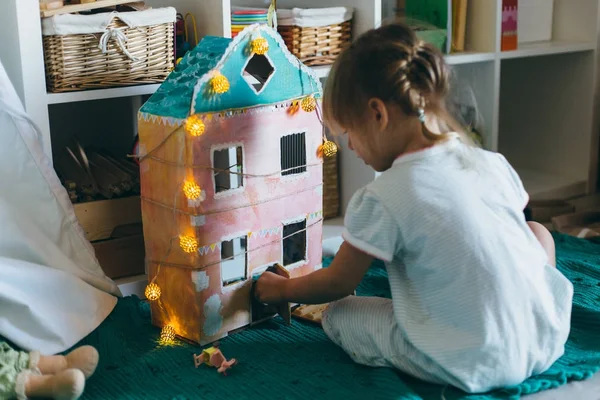 Маленька дівчинка грає з іграшковим будинком — стокове фото