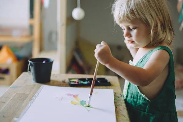 cute toddler girl drawing with paints, happy childhood concept