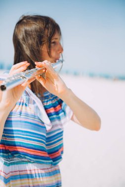 young beautiful woman playing the flute at beach clipart