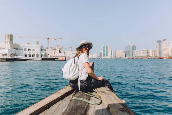 young beautiful woman sitting at boat and looking at sea and the city