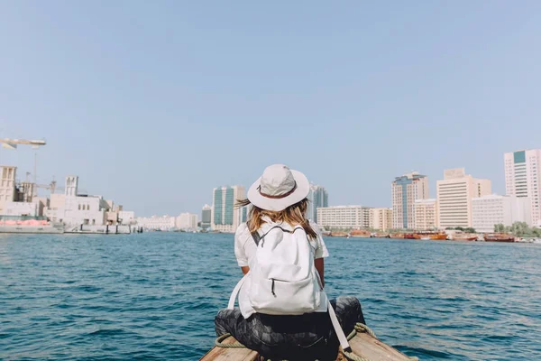 young beautiful woman sitting at boat and looking at sea and the city