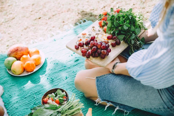 woman with healthy food relaxing at summer picnic