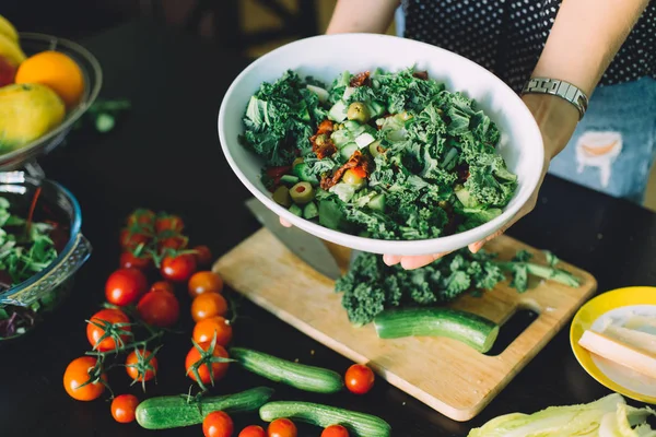 woman holding bowl with green veggie salad and fresh ingredients, healthy food