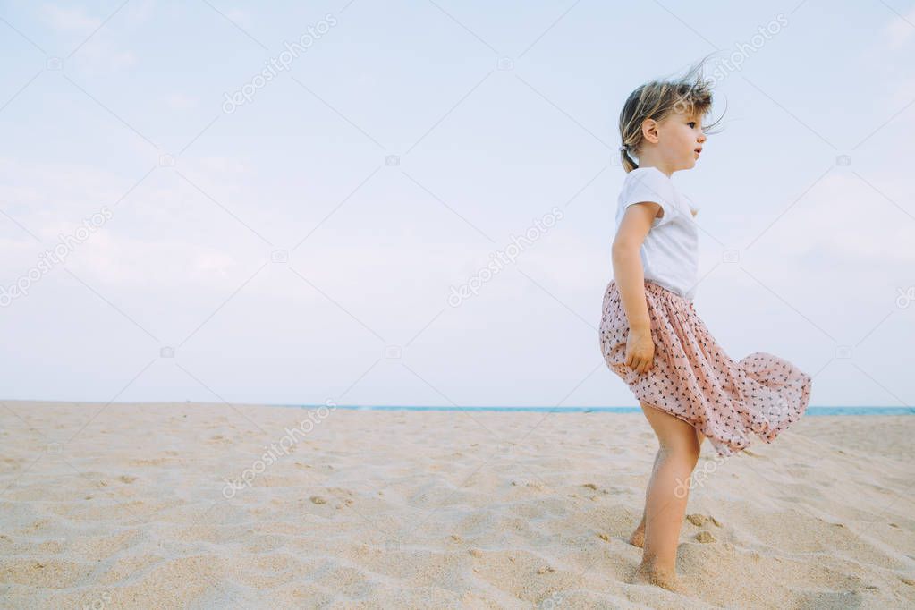adorable little girl walking at sandy beach 