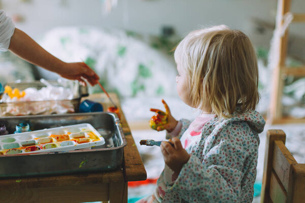 portrait of happy adorable little girls drawing with paints at home, closeup