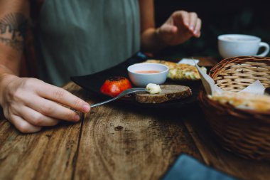 Kahvaltını bir kafede yapan bir kadının yakın plan fotoğrafı. Ekmek, sebzeli omlet ve domates..