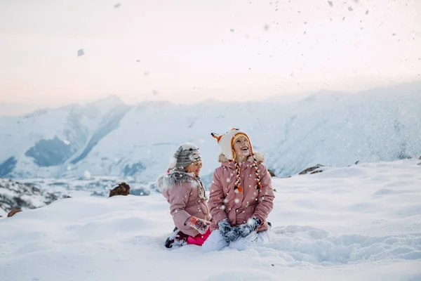 Две Девушки Сидящие Снегу Рыскающие Снежинках — стоковое фото