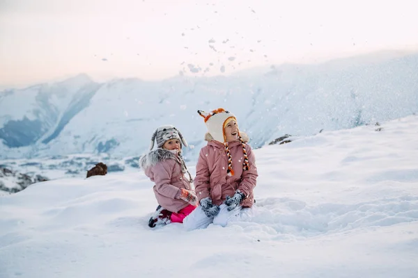 Две Девушки Сидящие Снегу Рыскающие Снежинках — стоковое фото