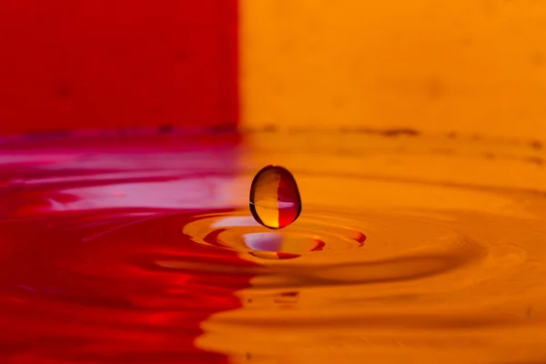 Kapky, spreje, tryskající vody na barevné pozadí — Stock fotografie