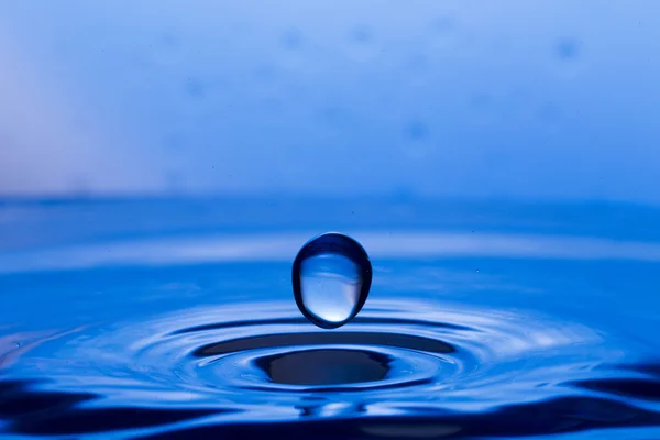 Gotas, aerosoles, salpicaduras de agua sobre un fondo colorido —  Fotos de Stock