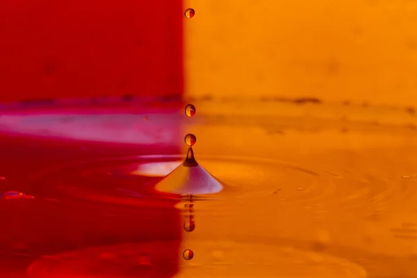 Tropfen, Sprays, Wasserspritzer auf buntem Hintergrund — Stockfoto