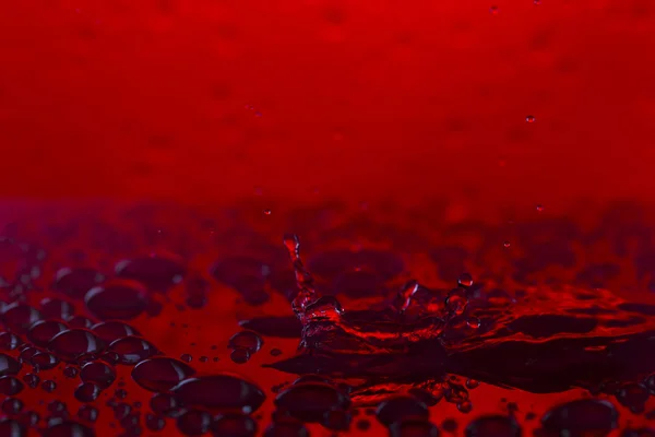 Kapky, spreje, tryskající vody na barevné pozadí — Stock fotografie