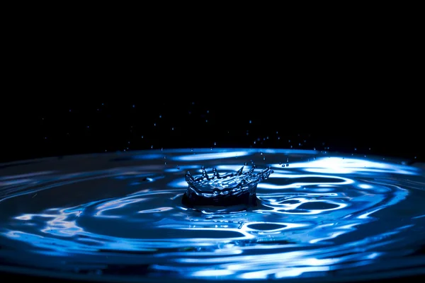 Sprays, druppels, plonsen van het water op een kleurrijke achtergrond — Stockfoto