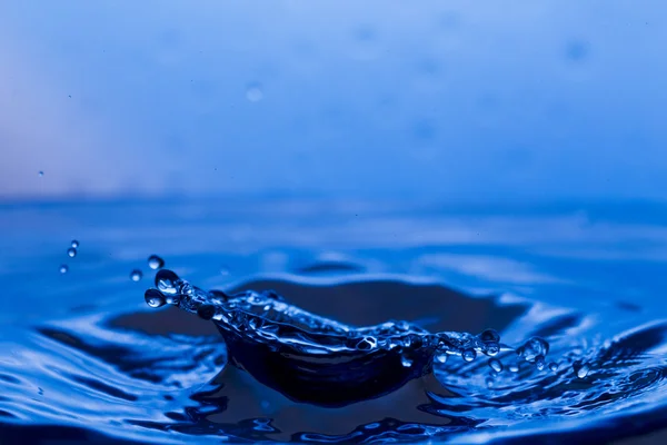 Gotas, aerosoles, salpicaduras de agua sobre un fondo colorido — Foto de Stock