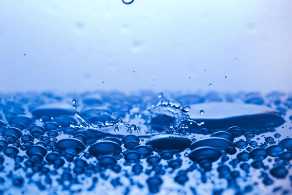 Gotas, sprays, salpicos de água em um fundo colorido — Fotografia de Stock