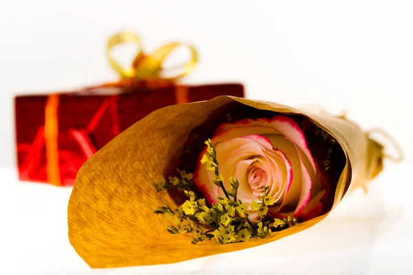 Bouquet di fiori in carta pergamena e regalo avvolto su un foglietto — Foto Stock