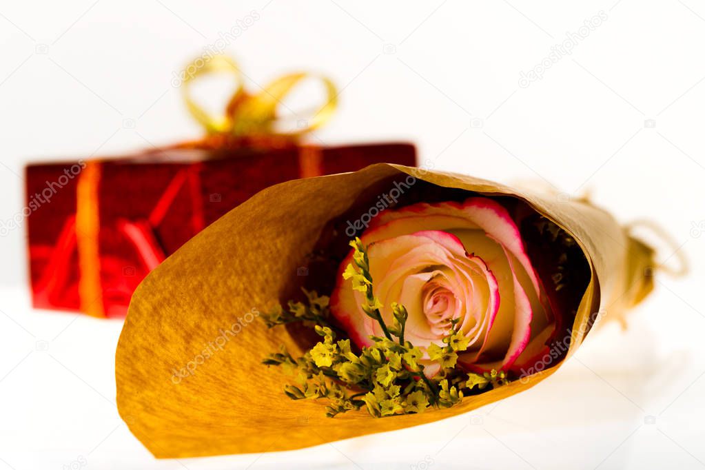 Bouquet of flowers in parchment paper and wrapped gift on a whit