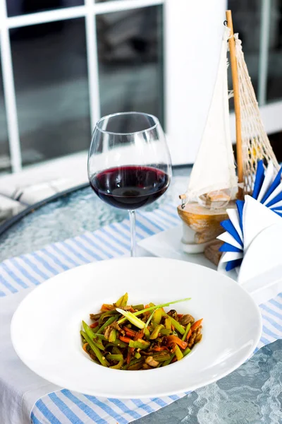 Мясо с овощами в тарелке и бокал красного вина — стоковое фото