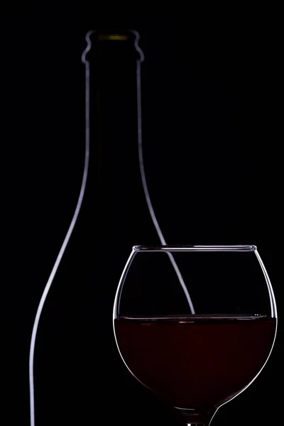 Ποτήρι κρασιού με μπουκάλι κρασί σε μαύρο φόντο, μινιμαλισμό, — Φωτογραφία Αρχείου