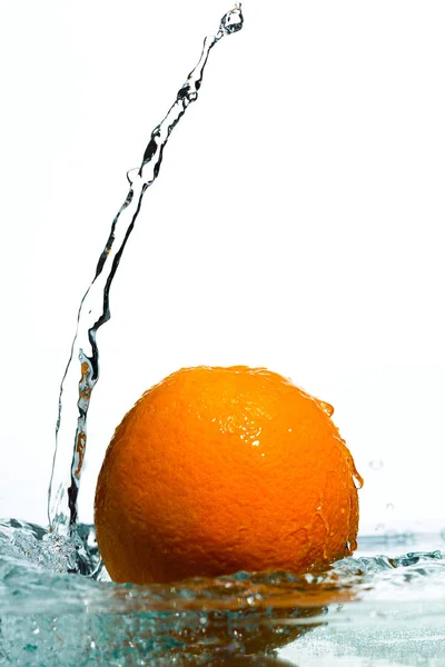 Orange in Wasserströmen auf weißem Hintergrund — Stockfoto