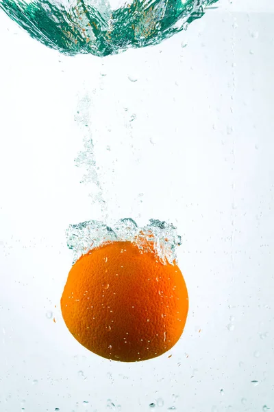 Оранжевый в потоках воды на белом фоне — стоковое фото