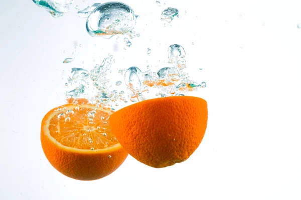 Orange in Wasserströmen auf weißem Hintergrund — Stockfoto