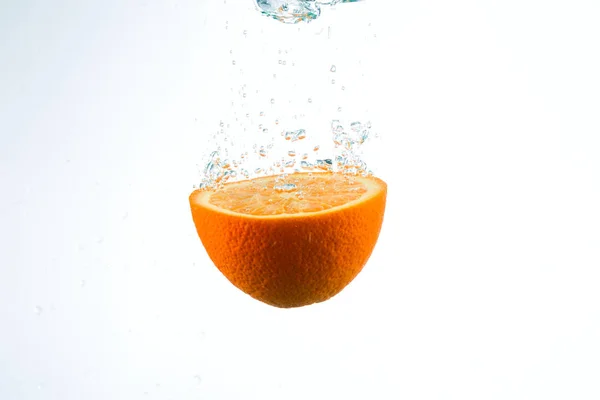 Orange in Wasserströmen auf weißem Hintergrund — Stockfoto