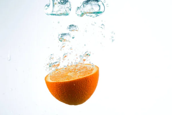 Orange in Wasserströmen auf weißem Hintergrund — Stockfoto