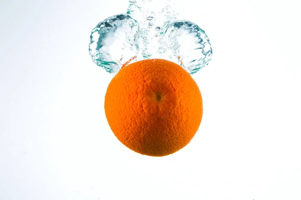 Laranja em correntes de água sobre um fundo branco — Fotografia de Stock