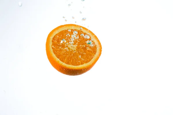 Orange in Wasserströmen auf weißem Hintergrund — Stockfoto