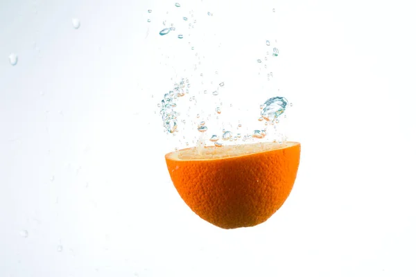 Orange in Wasserströmen auf weißem Hintergrund — Stockfoto