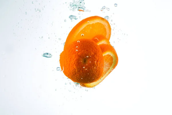 Orange in Wasserströmen auf weißem Hintergrund — Stockfoto