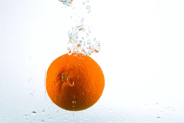 Оранжевый в потоках воды на белом фоне — стоковое фото