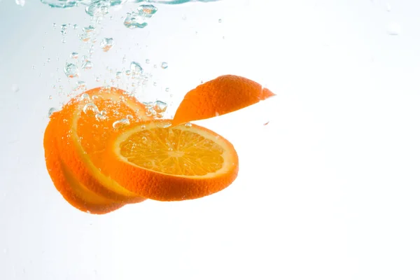 Orange in Wasserströmen auf weißem Hintergrund — Stockfoto