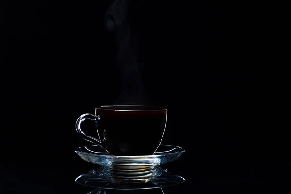 Café preto quente em uma xícara de vidro transparente em um fundo preto — Fotografia de Stock