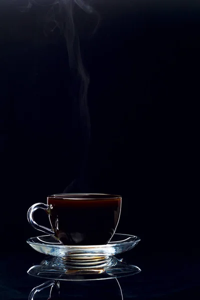 Café preto quente em uma xícara de vidro transparente em um fundo preto — Fotografia de Stock