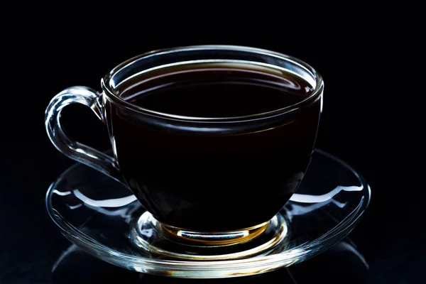 Café preto quente em uma xícara de vidro transparente em um fundo preto — Fotografia de Stock