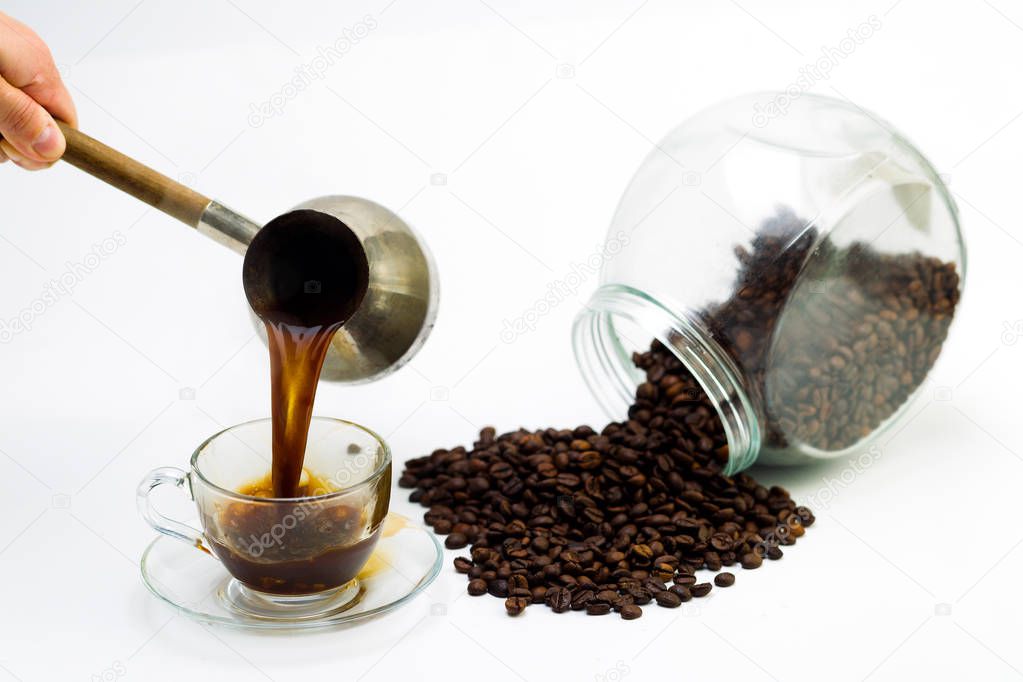 Black coffee in a glass cup and grains of coffee on a white back