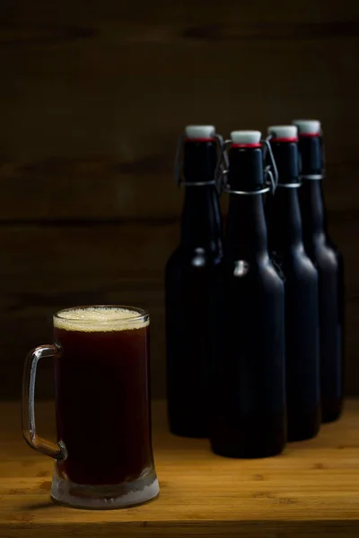 Vasos de cerveza y botellas de cerveza sobre un fondo de madera — Foto de Stock