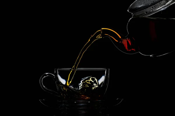 Transparent teapot with black tea on a black background — Stock Photo, Image