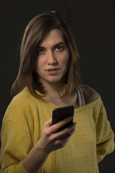 Молода емоційна дівчина зі смартфоном в жовтому светрі знову — стокове фото