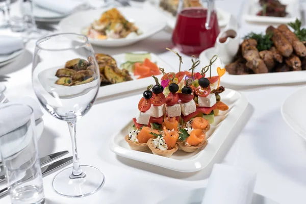 Set of canapes of fish, vegetables, meat on a plate on a white background. Buffet menu. Banquet menu