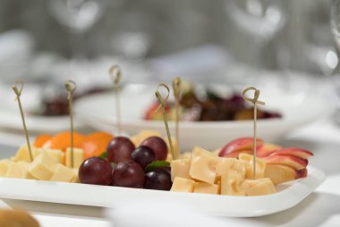 Ziyafet menüsü. Beyaz bir masa örtüsünde dilimlenmiş meyve ve peynir.