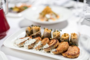 Beyaz soslu balık kekleri ve beyaz arka planda peynir ve otlarla doldurulmuş balık filetosu. Deniz ürünleri.