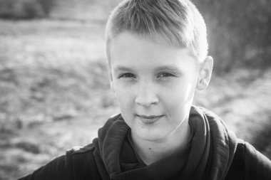 Genç bir çocuğun siyah beyaz portresi. Yüzünde çilleri olan, gülümseyen beyaz çocuğun yüzünü kapatın.. 