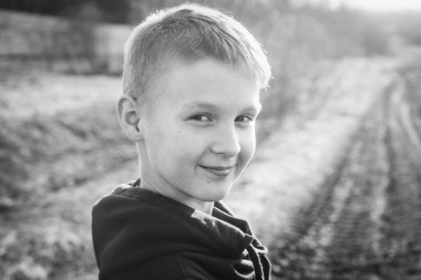 Genç bir çocuğun siyah beyaz portresi. Yüzünde çilleri olan, gülümseyen beyaz çocuğun yüzünü kapatın.. 