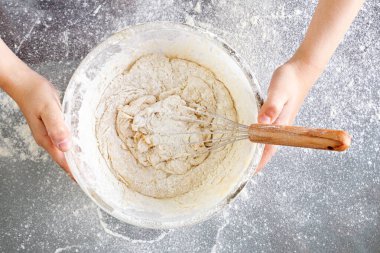 Yakınlarda hamur dolu cam bir kase var. Un, yumurta, süt ve şekerle lezzetli bir hamur çırp. Hamur pişmeye hazır. Cam masa. Serpiştirilmiş un..