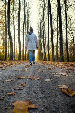 Arkadan Görünüm bir genç kızın ağaçları ile sınırlı bir yol yürüme 