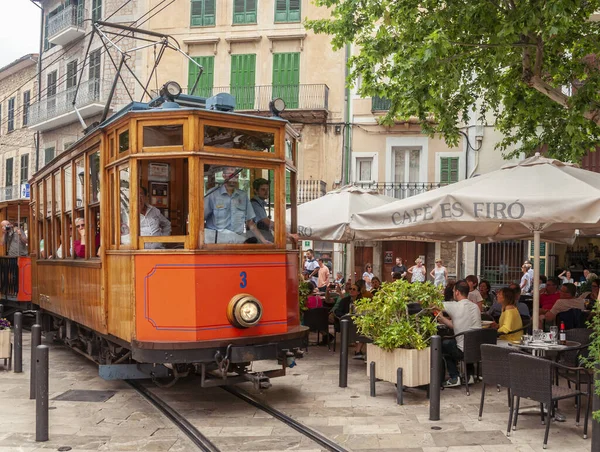 Soller 'ın tramvayı köyün ana meydanından geçiyor. Kafeterya teraslarında içki içen ve konuşan insanlar var.