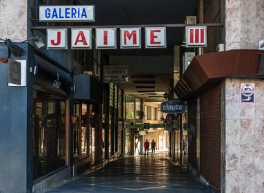 Güneşli bir pazar sabahı Palma de Mallorca 'da Jaime III alışveriş galerisi, dükkanlar kapalı ve arka planda iki insan silueti 